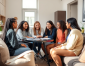 A group of six women engaged in a discussion around a small table in a cozy, modern living room. Ask Before Renting Furnished Student Properties
